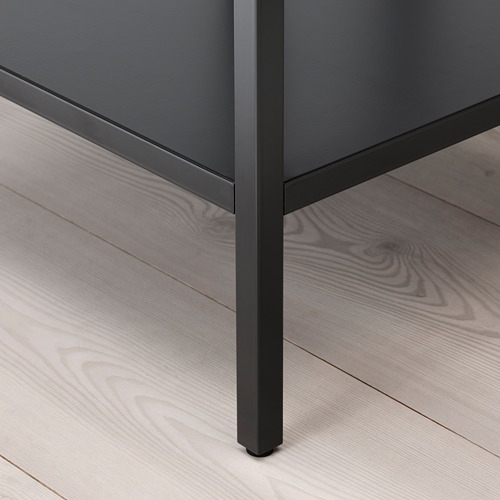 Primer plano de la pata del armario moderno. Metal oscuro con un ligero brillo, construcción robusta, que descansa sobre un elegante suelo de madera.