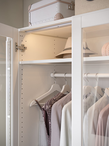 El armario blanco PAX almacena ropa, sombreros en estantes organizados y percheros para colgar.