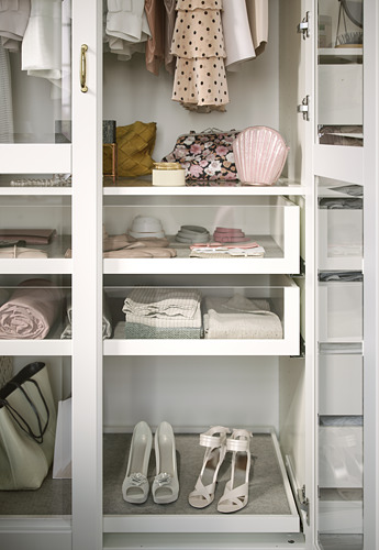 Un armario blanco con estantes de vidrio exhibe ropa y accesorios cuidadosamente organizados.
