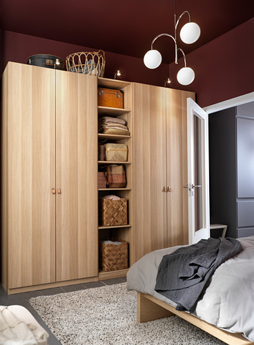 Wooden PAX wardrobe with baskets, pendant lights, grey rug, dark bed blanket, red walls.