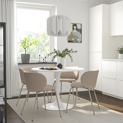 Moderno comedor con sillas KRYLBO, mesa blanca, jarrón, velas y luz. Habitación luminosa con gran ventanal, planta y pintura.
