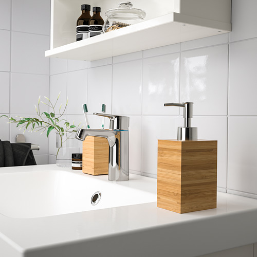 Baño moderno con lavabo blanco, grifo cromado, dispensador de jabón de madera, soporte para cepillos de dientes y estante.