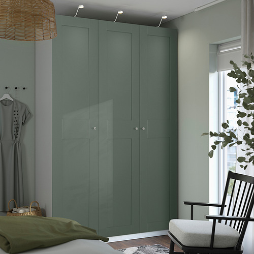 Dormitorio moderno con armario alto PAX gris, lámpara colgante de mimbre, silla y planta.
