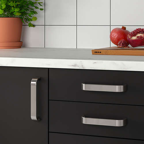 Cocina moderna con armarios negros, con tiradores KALERUM y encimera de mármol. Se exhiben una granada y un cuchillo.