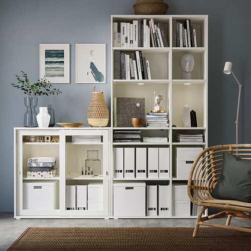 Moderna oficina en casa con almacenamiento blanco VIHALS, libros, decoración, silla de mimbre y lámpara de pie.