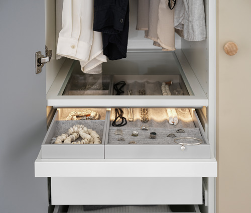 Organizador de joyas KOMPLEMENT con inserciones de fieltro blanco y compartimentos para anillos, collares y relojes.