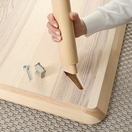 Montaje a mano de una mesa de madera ligera, probablemente la LISABO, con herramientas y herrajes visibles, lo que garantiza la estabilidad y la seguridad.