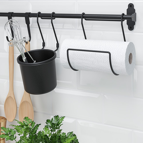 El riel HULTARP negro sostiene el carrito de utensilios, toallas de papel y utensilios de cocina contra la pared de azulejos blancos.