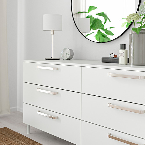 Cómoda blanca con asas metálicas; Incluye lámpara, reloj y espejo.
