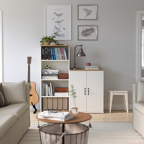 Sala de estar con aparador SKRUVBY, guitarra, estantería, mesa de centro, dos sofás, lámpara y muebles acabados en roble contra una pared azul claro.