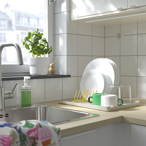 Fregadero de cocina moderno con un escurridor de platos con platos y utensilios limpios, incluido un dispensador de plantas y jabón cerca.