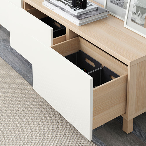 Open wooden desk drawer with storage bins, showcasing organized interior.