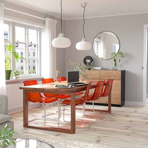 Comedor luminoso con una moderna mesa de madera MÖRBYLÅNGA, sillas naranjas y grandes ventanales. Luminoso, aireado y espacioso.