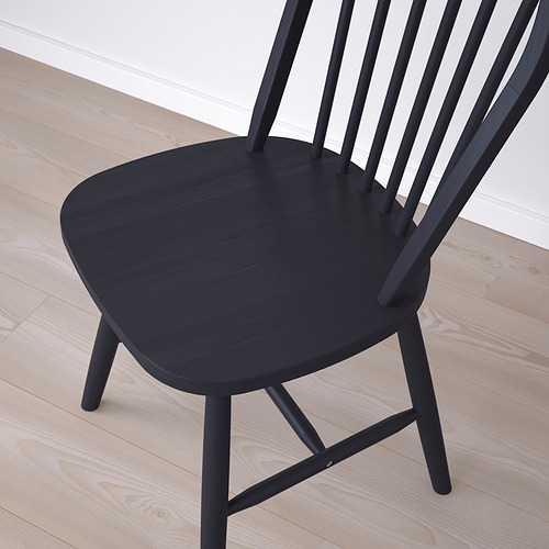 Silla moderna de madera negra con diseño elegante y construcción robusta, colocada sobre suelo de madera clara.