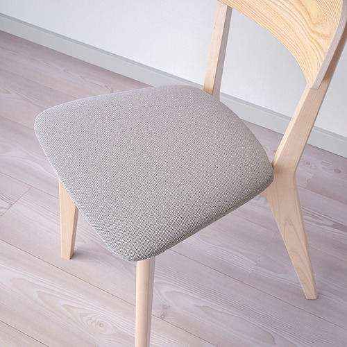 Silla moderna de madera con respaldo curvo, con asiento de tela afelpada, colocada sobre suelo de madera clara.