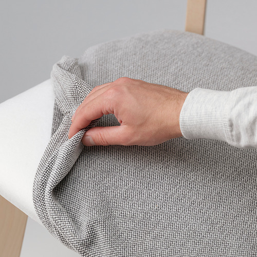 Funda de silla de tela gris tirada a mano sobre mesa blanca con patas de madera.