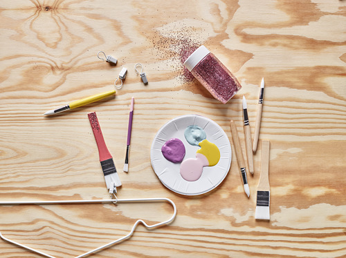 Materiales de arte: pinceles, paleta, pintura, purpurina sobre mesa de madera.