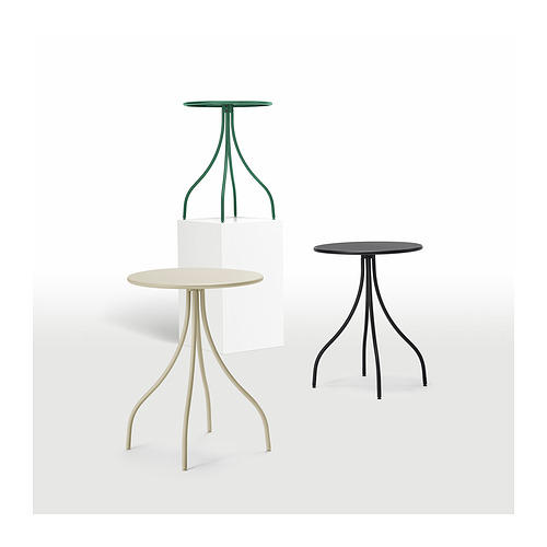Tres mesas auxiliares en verde, beige y negro con patas delgadas estilo trípode y tapas redondas. Diseño moderno y minimalista.