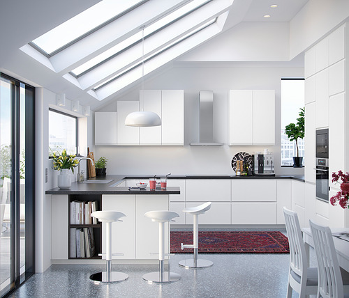 Cocina blanca moderna con gabinetes elegantes, encimera negra, taburetes de bar y tragaluces.