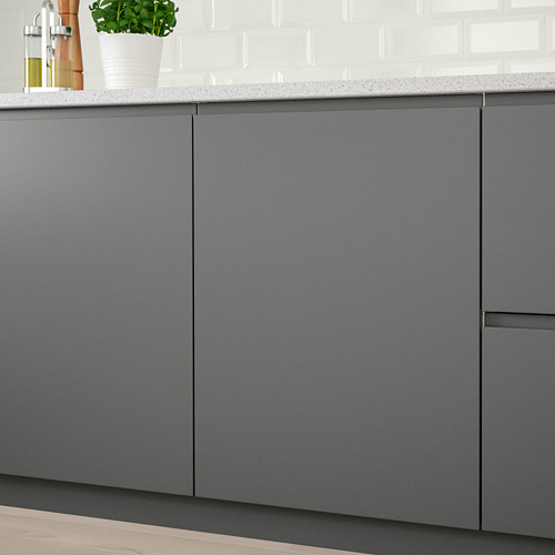 Modernos armarios de cocina con puertas sin tiradores y tiradores integrados en color gris oscuro, montados sobre una encimera de color claro que muestra una planta verde.