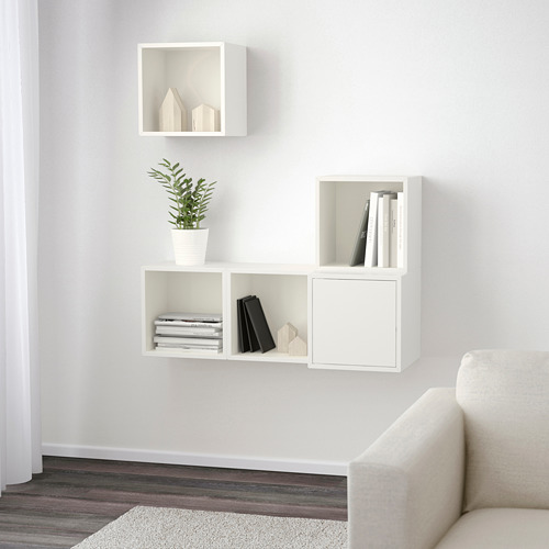 Estantería de pared minimalista en color blanco. Tres compartimentos contienen libros, una planta y decoración. Solución de almacenamiento eficiente.