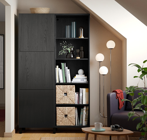 Sala de estar moderna con estanterías BESTÅ, plantas y un sillón gris. Acogedor y elegante.