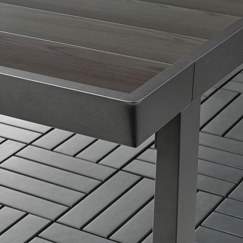Mesa de exterior moderna con tapa similar a la madera oscura y elegante marco de metal, diseñada para brindar durabilidad y facilidad de limpieza.