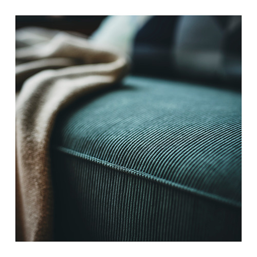 Sofá KIVIK en tejido de pana verde azulado, primer plano de la textura del cojín del asiento y costuras.