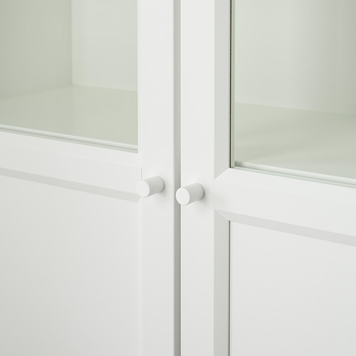 Gabinete con frente de vidrio blanco con manijas de puerta redondeadas, reflectando la luz, mostrando un diseño elegante.