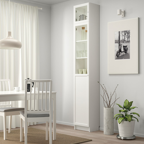 Comedor blanco con mueble BILLY, cristalería, planta verde, arte de pared.