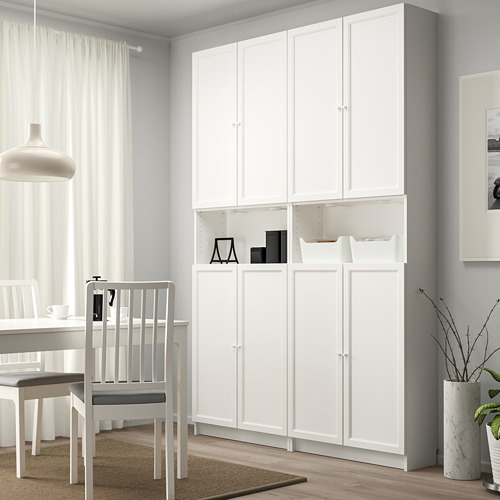 Comedor moderno con estantería BILLY blanca, cortinas transparentes y lámpara colgante blanca.