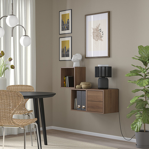 Habitación minimalista con mueble de madera EKET, silla de arte, planta y mimbre.