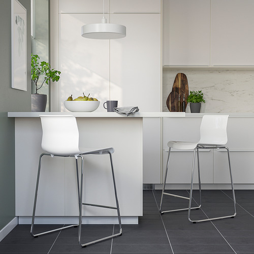 Cocina moderna con taburetes GLENN blancos. Elegantes patas cromadas, cómodos asientos blancos. Luz colgante, plantas en macetas, frutas en el mostrador.