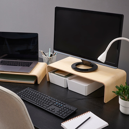 Wooden monitor stand with laptop, keyboard storage, on dark desk. Includes lamp, plant, wireless keyboard, and notepad for efficient workspace.