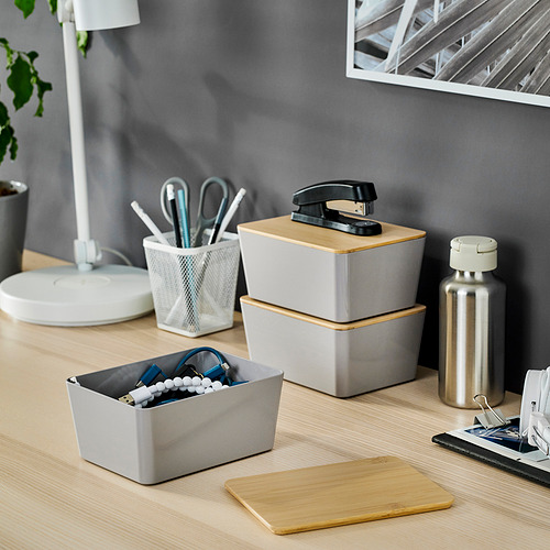 Escritorio con cajas KUGGIS que contienen material de oficina y gadgets.