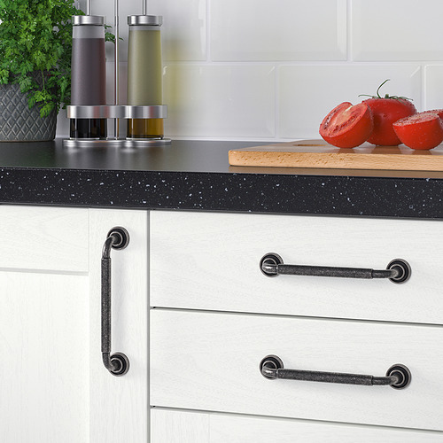 Cocina moderna con encimeras moteadas de negro, gabinetes blancos con manijas oscuras y hierbas frescas.