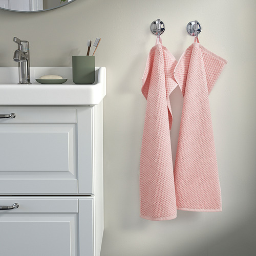 Baño con tocador de madera, lavabo, accesorio cromado, cepillos de dientes, toallas rosas.