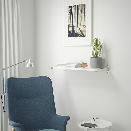 Moderno espacio de trabajo con silla de oficina azul, mesa redonda y estantería con plantas y arte.