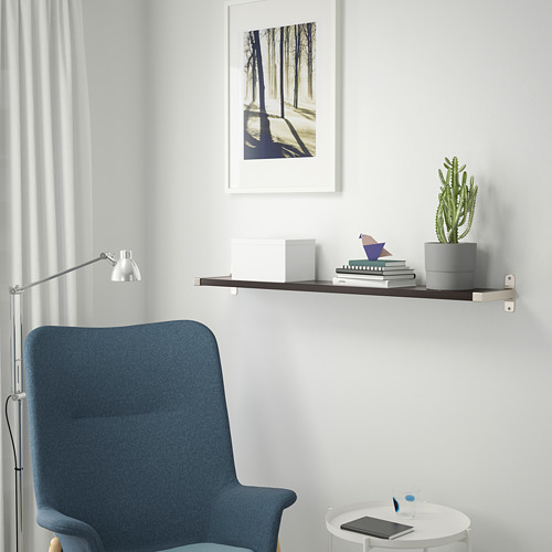 Silla azul, cactus, libros, cuadro y tableta sobre mesa blanca.