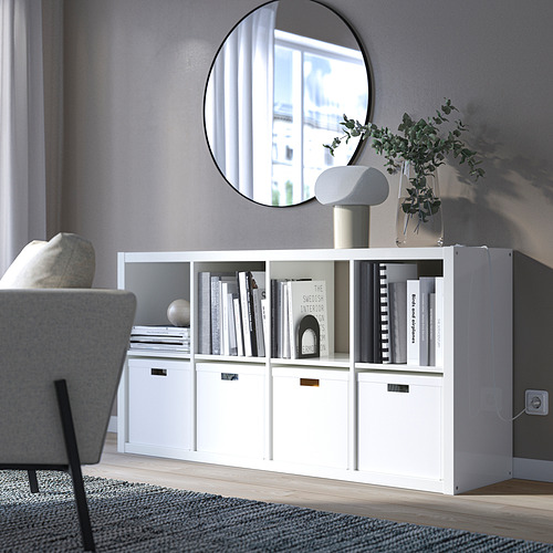 Estantería KALLAX con libros, espejo, silla, planta, lámpara.