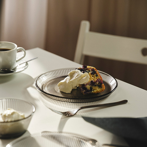 Bizcocho con nata montada, café y tenedor sobre una mesa de madera.