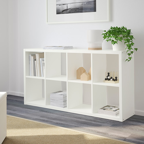 Estantería blanca FLYSTA con libros, decoración, velas y plantas.