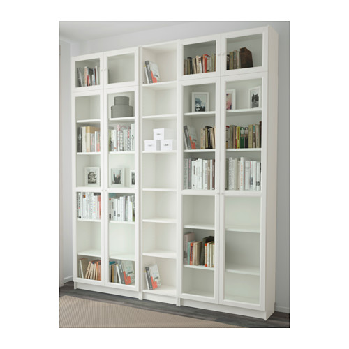 Gran estantería blanca con puertas de cristal, donde se exhiben libros y objetos de decoración, anclada a la pared.