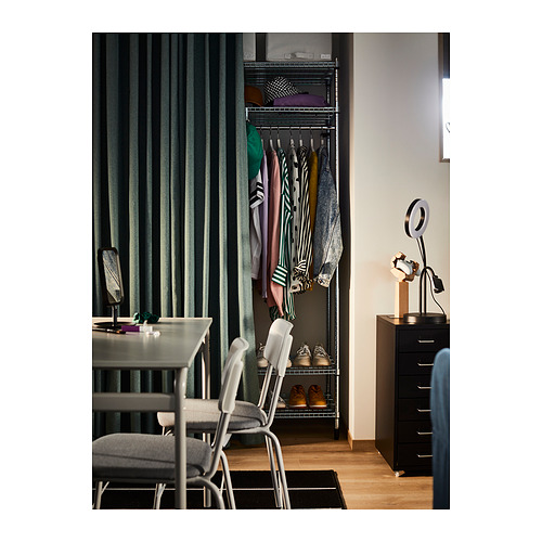 Dormitorio con armario abierto, cortinas verdes, mesa moderna y armario de almacenaje negro.