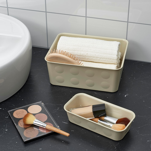 Barra de baño con cosméticos organizados y toallas. Dos cajas de plástico almacenan brochas de maquillaje, base de maquillaje y toallas dobladas, optimizando el espacio.