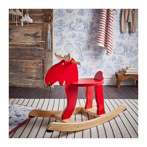 El juguete del caballo mecedora rojo brillante con detalles de madera se asienta sobre una alfombra a rayas. Elemento de juego perfecto para niños con decoración rústica.