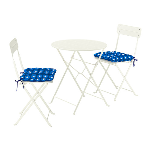 Una mesa de exterior blanca con dos sillas plegables a juego y cojines azules. Diseño moderno y compacto, ideal para balcones.