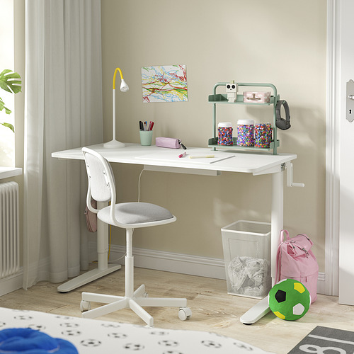Un escritorio ajustable blanco para niños con una silla gris, accesorios coloridos y un estante verde.