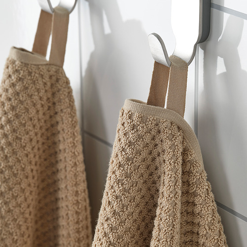 Dos toallas beige cuelgan cuidadosamente en ganchos. Algodón suave y absorbente; Ideal para el uso diario.