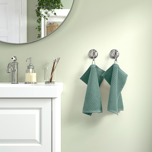 Baño verde con tocador blanco y toallas GULVIAL. Fregadero con accesorios cromados.